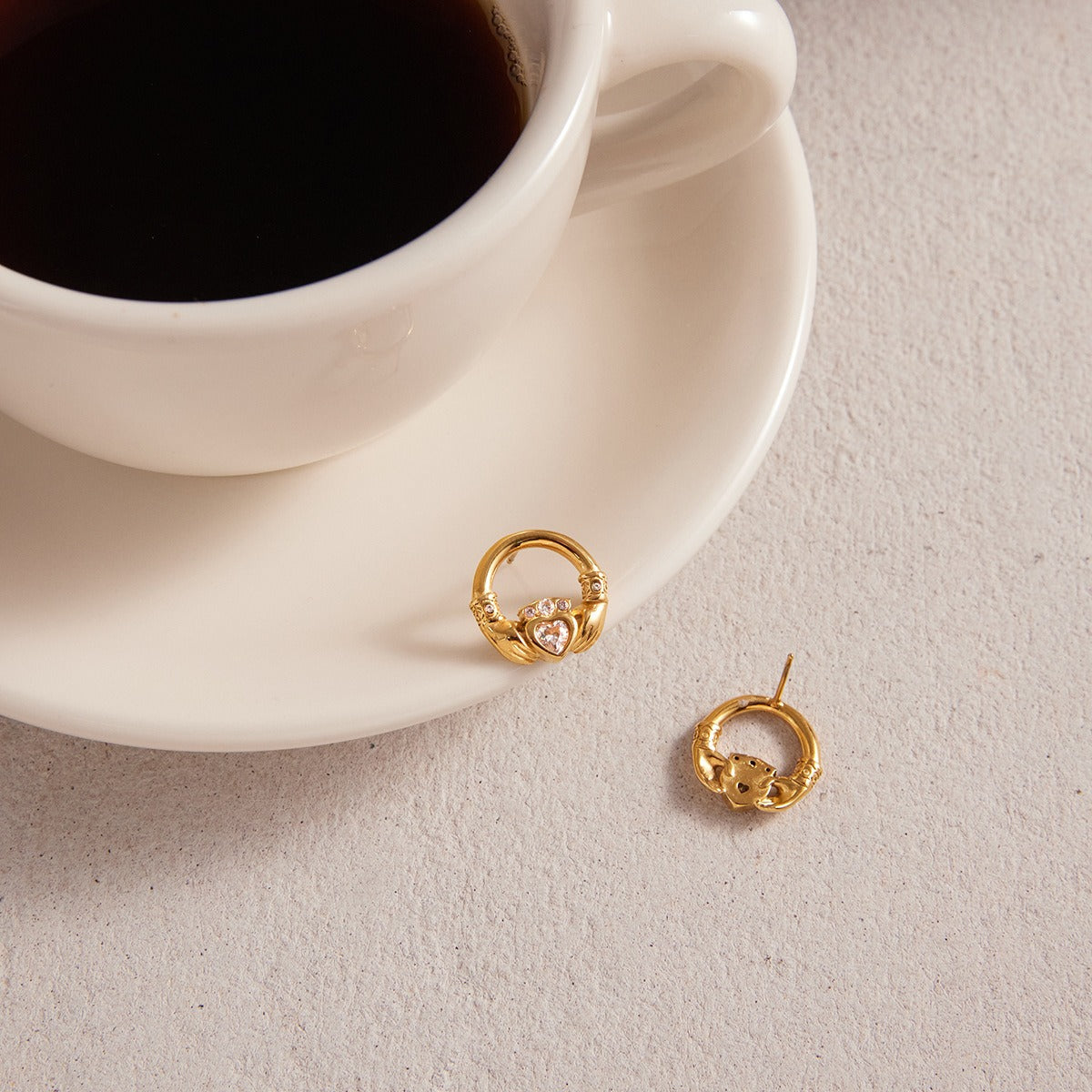 18K gold-plated friendship hand design titanium steel stud earrings with cubic zirconia.