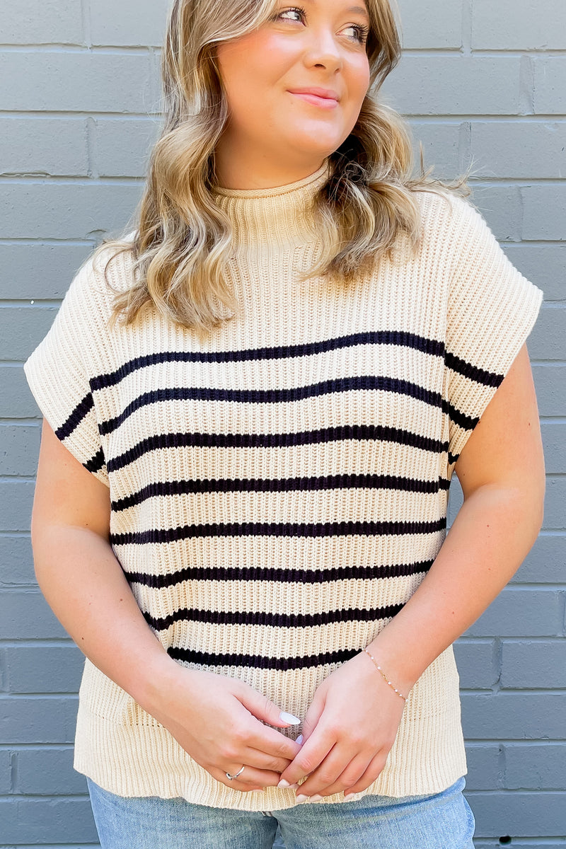 Cream colored sleeveless, mock neck sweater with stripes.